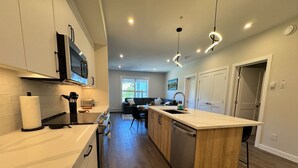 Eine moderne Küche mit einer zentralen Kochinsel, Edelstahlgeräten und einem Essbereich mit Sofa und Tisch.
