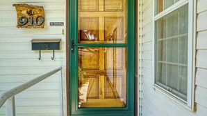 Une porte d’entrée avec un cadre vert, une boîte aux lettres et un panneau indiquant « Pas de démarcheurs ».