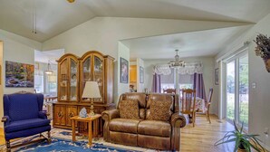 Un salon spacieux avec un fauteuil bleu, un canapé en cuir marron, un meuble en bois et un grand tapis.