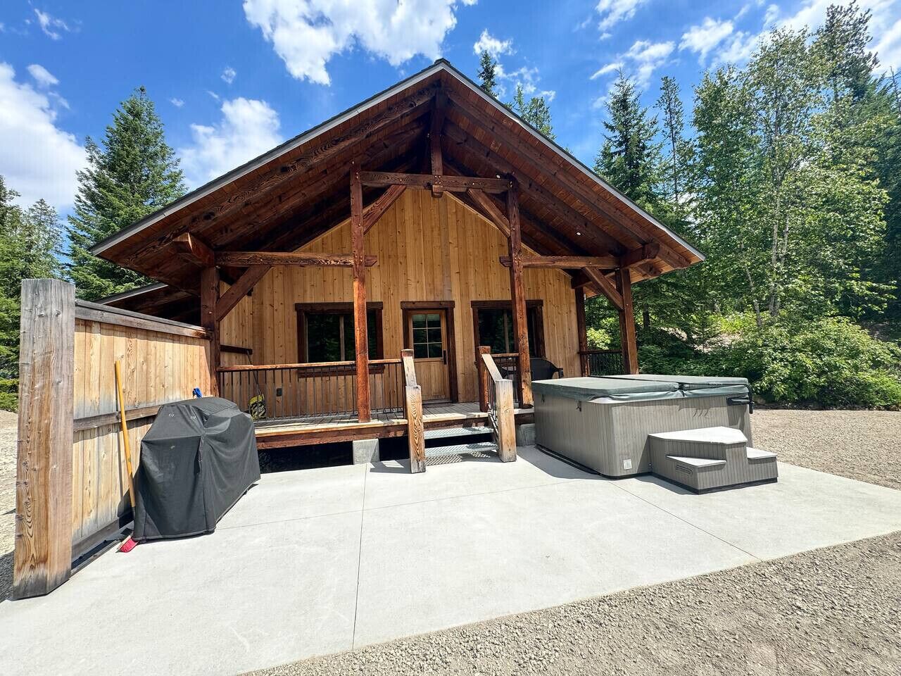 Een houten chalet met een overdekte veranda, een hottub en een barbecue.