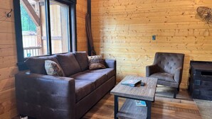 Una habitación acogedora con un sofá de cuero marrón, una mesa de centro de madera y un sillón tapizado.