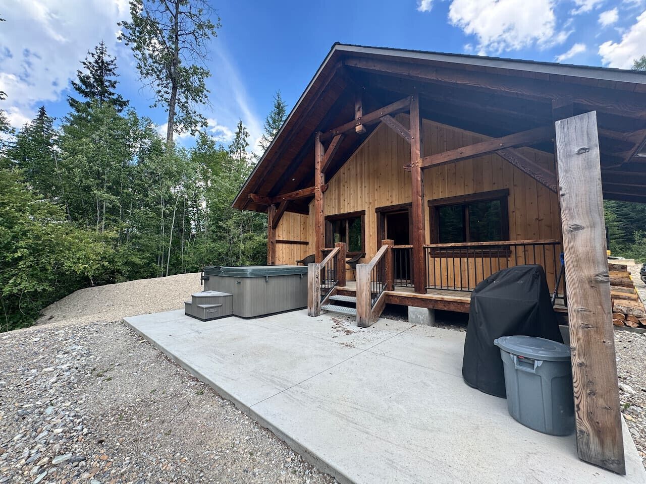 Une cabane en bois avec une véranda, un espace salon extérieur et un jacuzzi.