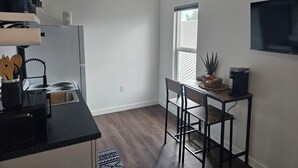 Una cocina moderna con refrigerador, estufa y comedor con sillas y mesa.