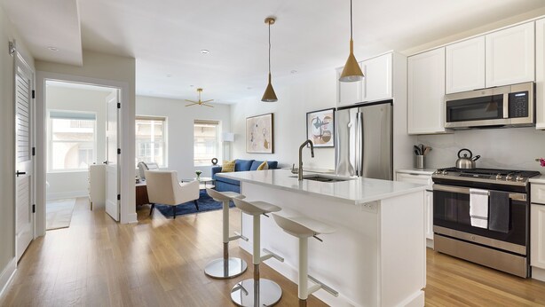 A modern kitchen with white cabinetry, stainless steel appliances, and a central island with bar stools. - Sunny 2BR Loft Work Relax Minutes to NYC (Hoboken)