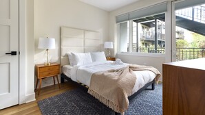 A bedroom with a large bed, two bedside tables, a window with a view of a balcony, and a door. - Sunny 2BR Loft Work Relax Minutes to NYC (Hoboken)
