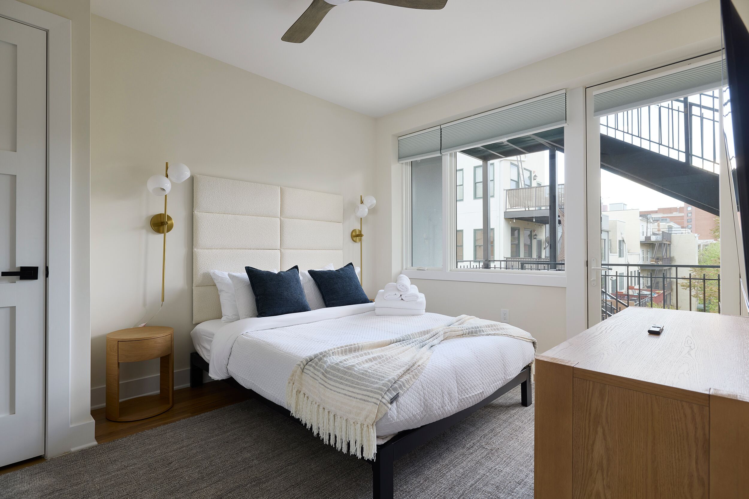 Un dormitorio con cama, mesita de noche y vistas al exterior.