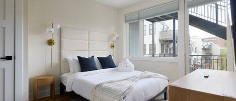 Un dormitorio con cama, mesita de noche y vistas al exterior.