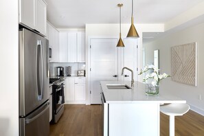 A modern kitchen with stainless steel appliances, a white countertop, and pendant lighting. - Bright 3BR Loft Hoboken Gem (Hoboken)