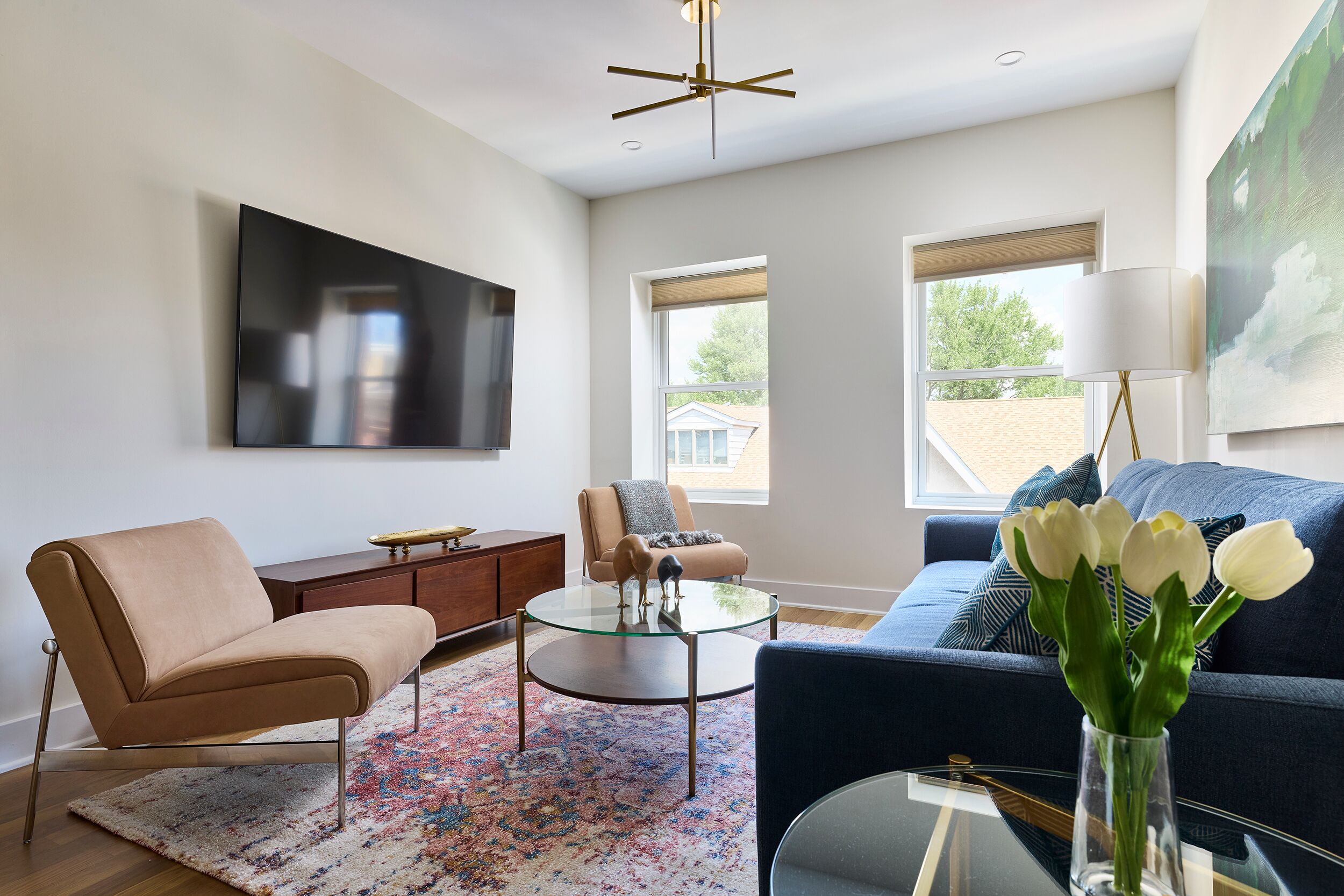 A modern living room with a sofa, armchair, coffee table, and a TV mounted on the wall.