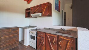 A kitchen with wooden cabinets, a stove, and a sink.