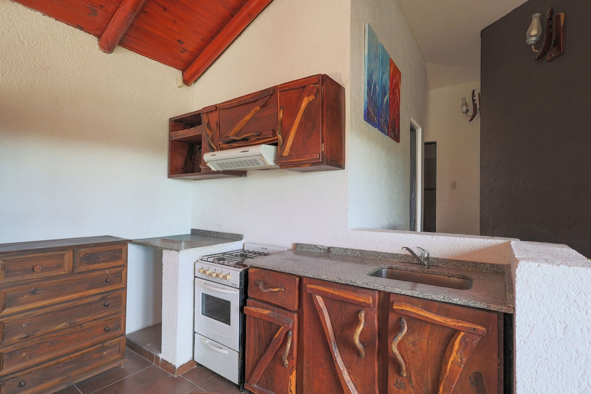 Une cuisine avec des meubles de rangement en bois, une cuisinière et un évier.