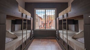 A dormitory room with bunk beds, a large window, and a view of the outside.