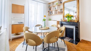 Un coin repas comprenant une table ronde, six chaises, une cheminée et une bibliothèque.