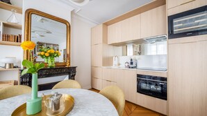 Une cuisine moderne avec des meubles en bois, un four encastré et un grand miroir au-dessus du plan de travail.