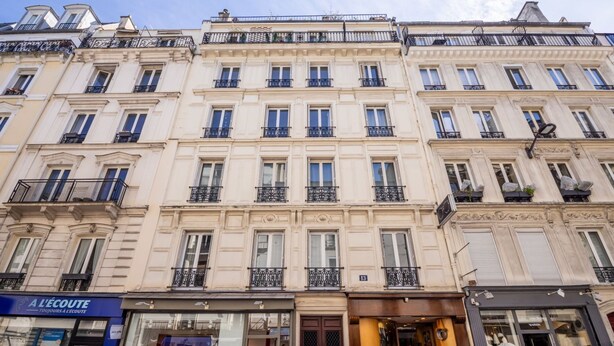 Un immeuble à plusieurs étages, de style architectural classique, caractérisé par des fenêtres et des balcons régulièrement espacés.