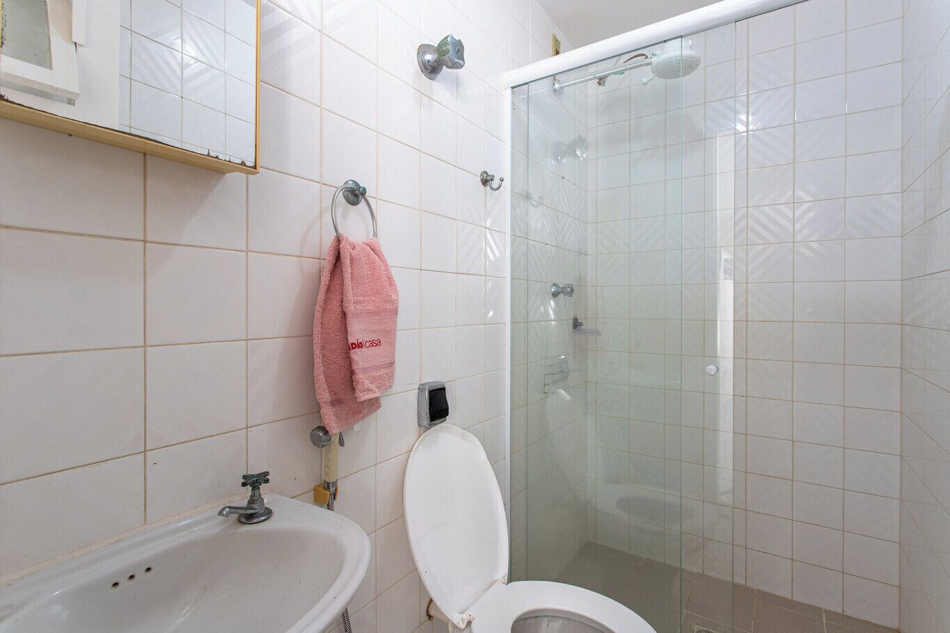 A bathroom with a white sink, toilet, and glass-enclosed shower.