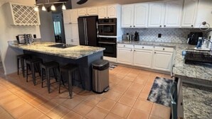 A spacious kitchen with a large island, white cabinets, and a tiled floor. - The Sleepy Hollow Hideaway (Gold Canyon)