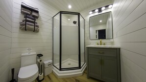 Une salle de bain avec une douche à parois de verre, des toilettes, un lavabo avec des robinets dorés et un porte-serviettes avec des serviettes.