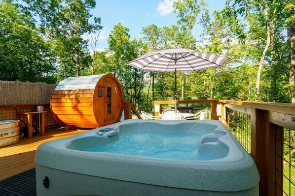 Ein Whirlpool auf einer Holzterrasse mit einer Sauna und einem Sonnenschirm.