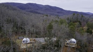 Une cabane isolée, dotée d’une grande antenne parabolique, entourée d’une forêt dense et de montagnes.