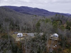 Eine abgelegene Holzhütte mit einer großen Satellitenschüssel, umgeben von dichtem Wald und Bergen.