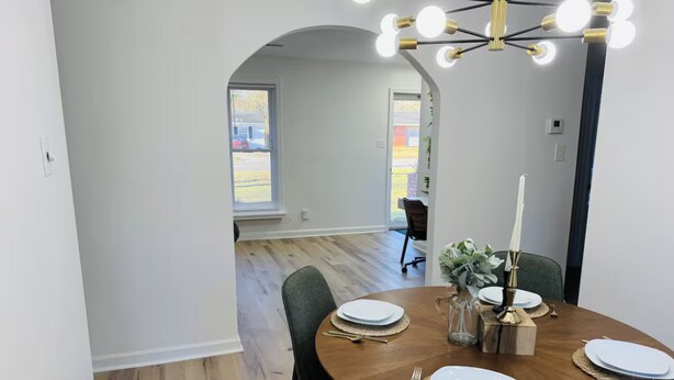 A dining area with a round table set for four, a chandelier, and a view through an archway to another room. - Redbud: Waterfront, Augusta Canal, 3BR, king bed (Augusta)