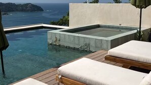 Ein Poolbereich mit Liegestühlen und Blick auf den Ozean.