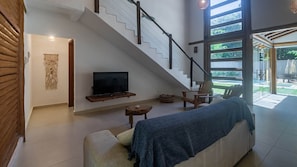 Ein modernes Wohnzimmer mit Treppe, Flachbildfernseher, Sofa und Couchtisch.