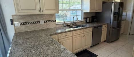 A kitchen with granite countertops, stainless steel appliances, and light-colored cabinetry.