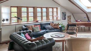 A cozy living room with a dark blue sofa, a round coffee table, and a high ceiling with skylights.