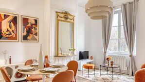 A dining area with a round table, orange chairs, a television, and a large mirror. - Le Lauroise, magnifique F2 place des Carmes (Rouen)