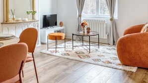 A modern living room with a large mirror, a television, and a sofa. - Le Lauroise, magnifique F2 place des Carmes (Rouen)