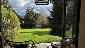Une terrasse avec des chaises en osier et une table en bois, donnant sur un jardin luxuriant.