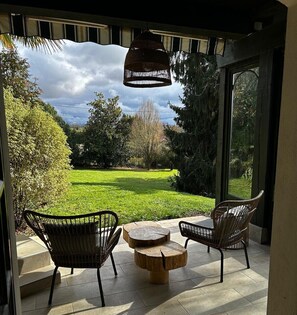 A patio with wicker chairs and a wooden table, overlooking a lush garden. - Villa Gustavine - Maison d'Architecte (Ger)