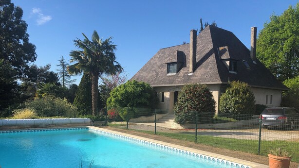 Une piscine avec une maison en arrière-plan.
