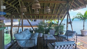 Eine Holzterrasse mit Gartenmöbeln, darunter Sofas und ein Tisch, mit Blick auf ein Gewässer.