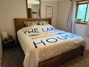 Un dormitorio con una cama adornada con un edredón que dice 'THE LAKE HOUSE'.