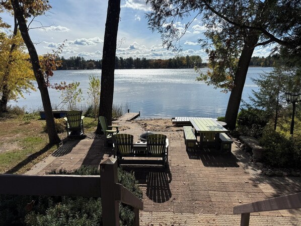 Un área de picnic junto al lago con bancos y mesas, rodeada de árboles y vistas al lago.