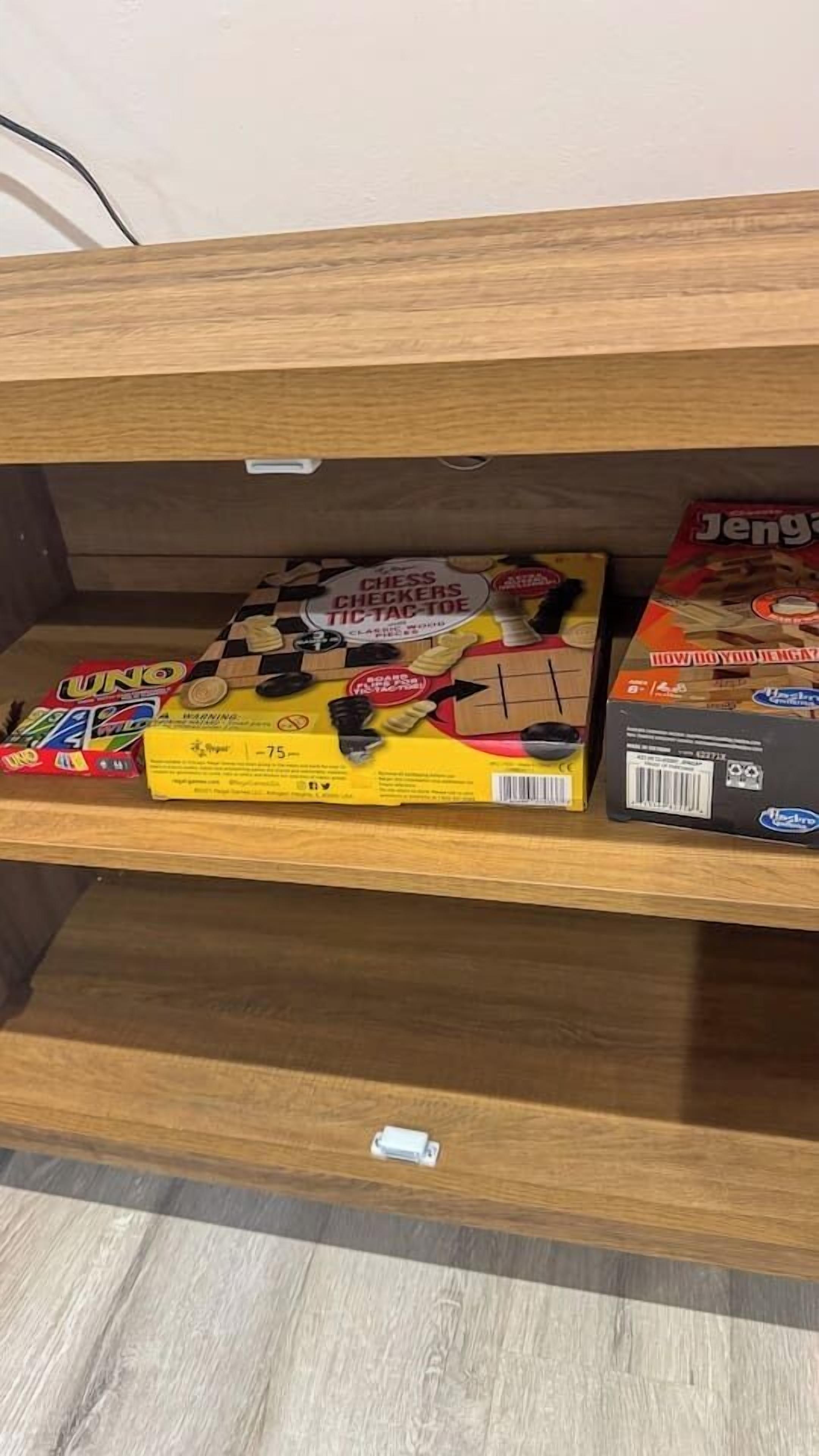 Uno scaffale di legno con un gioco da tavolo, una scatola di dama e un set degli scacchi.