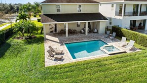 A two-story house with a covered patio and a swimming pool. - New 8BR Luxury Retreat • Pool & Spa • Near Disney (Kissimmee)