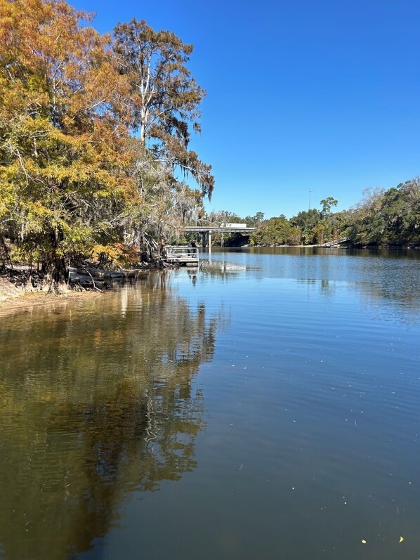 A calm river with a wooden dock and a bridge in the background.