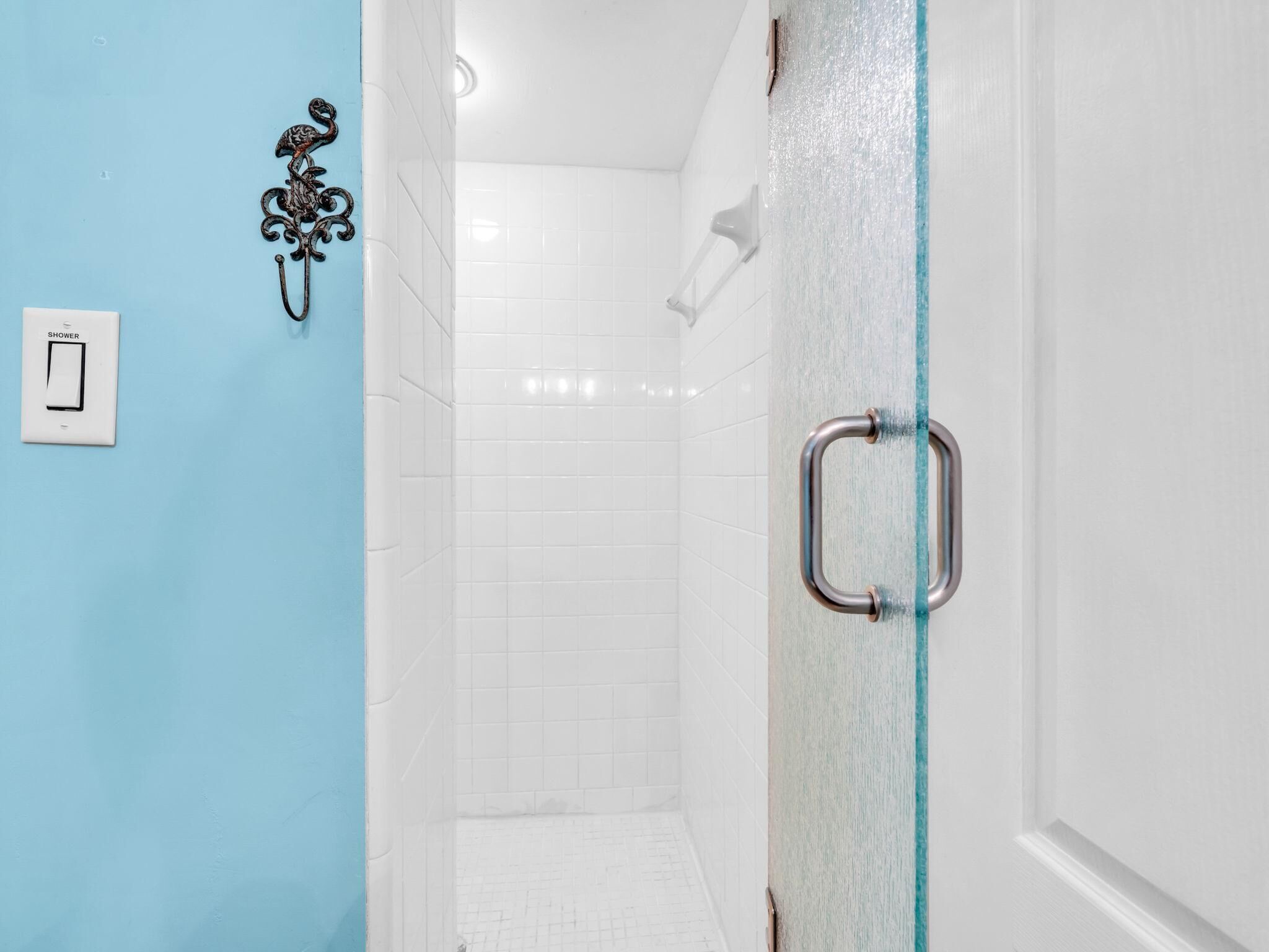 A bathroom with a shower, a glass door, and a white tiled shower area.