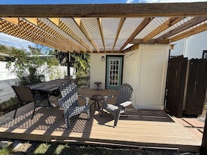 An outdoor patio with a wooden deck, a covered seating area with Adirondack chairs, and a small table. - Coastal Cottage / less than 1 mile to Nokomis Beach / Dog-Friendly FENCED YARD (Nokomis)