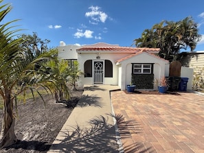 A single-story house with a red-tiled roof, a front door with a metal gate, and a paved driveway leading to the entrance. - Coastal Oasis / less than 1 mile to Nokomis Beach / Dog-Friendly FENCED YARD (Nokomis)