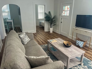 A living room with a sofa, a coffee table, a television, and a potted plant.