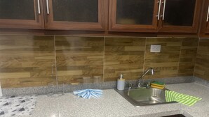 A kitchen with wooden cabinets, a granite countertop, a stainless steel sink, and a dish rack.
