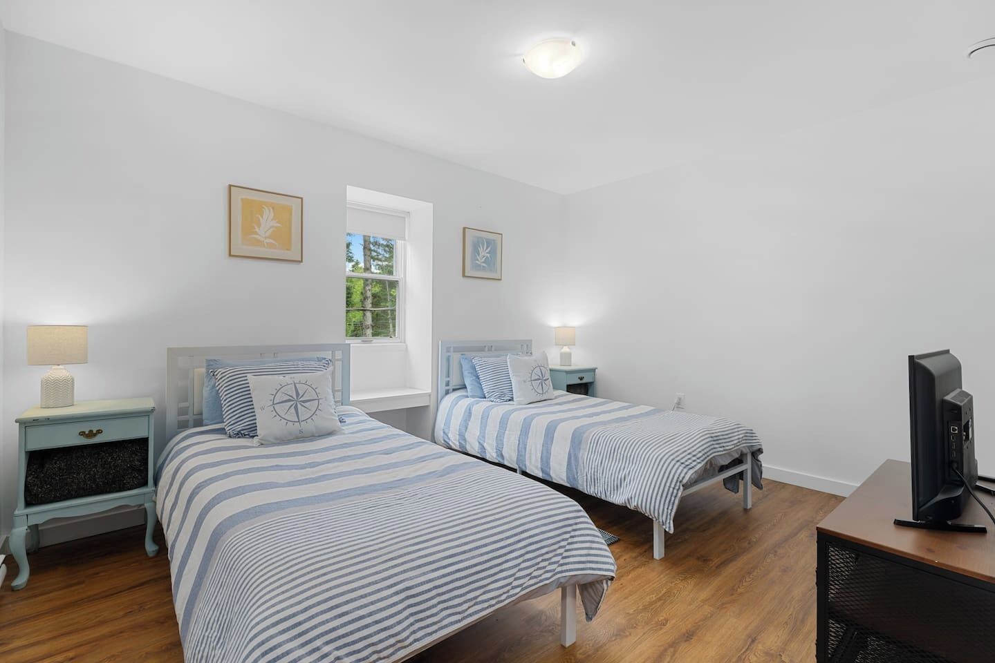 Une chambre avec deux lits, une télévision et une fenêtre.