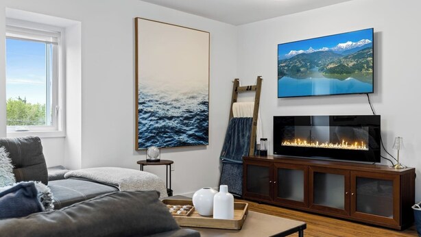 Una sala de estar moderna con un sofá, una chimenea, un televisor y obras de arte en las paredes.