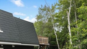 Un patio trasero con una zona de estar techada, una parrilla de barbacoa y una terraza de madera.