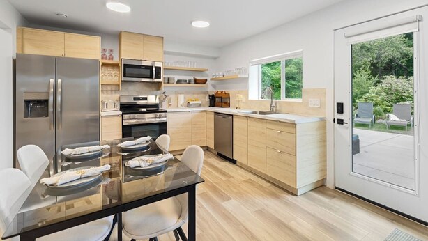 Una cocina moderna con electrodomésticos de acero inoxidable, armarios de madera y una mesa de comedor de vidrio.